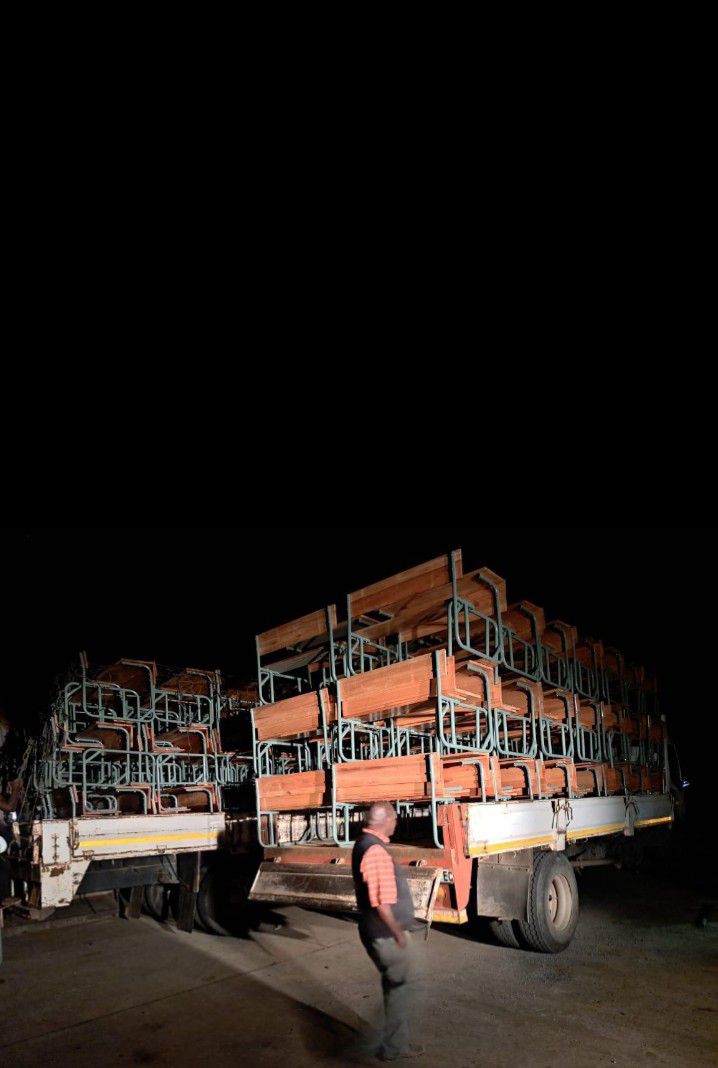 School desks loaded onto delivery trucks at night